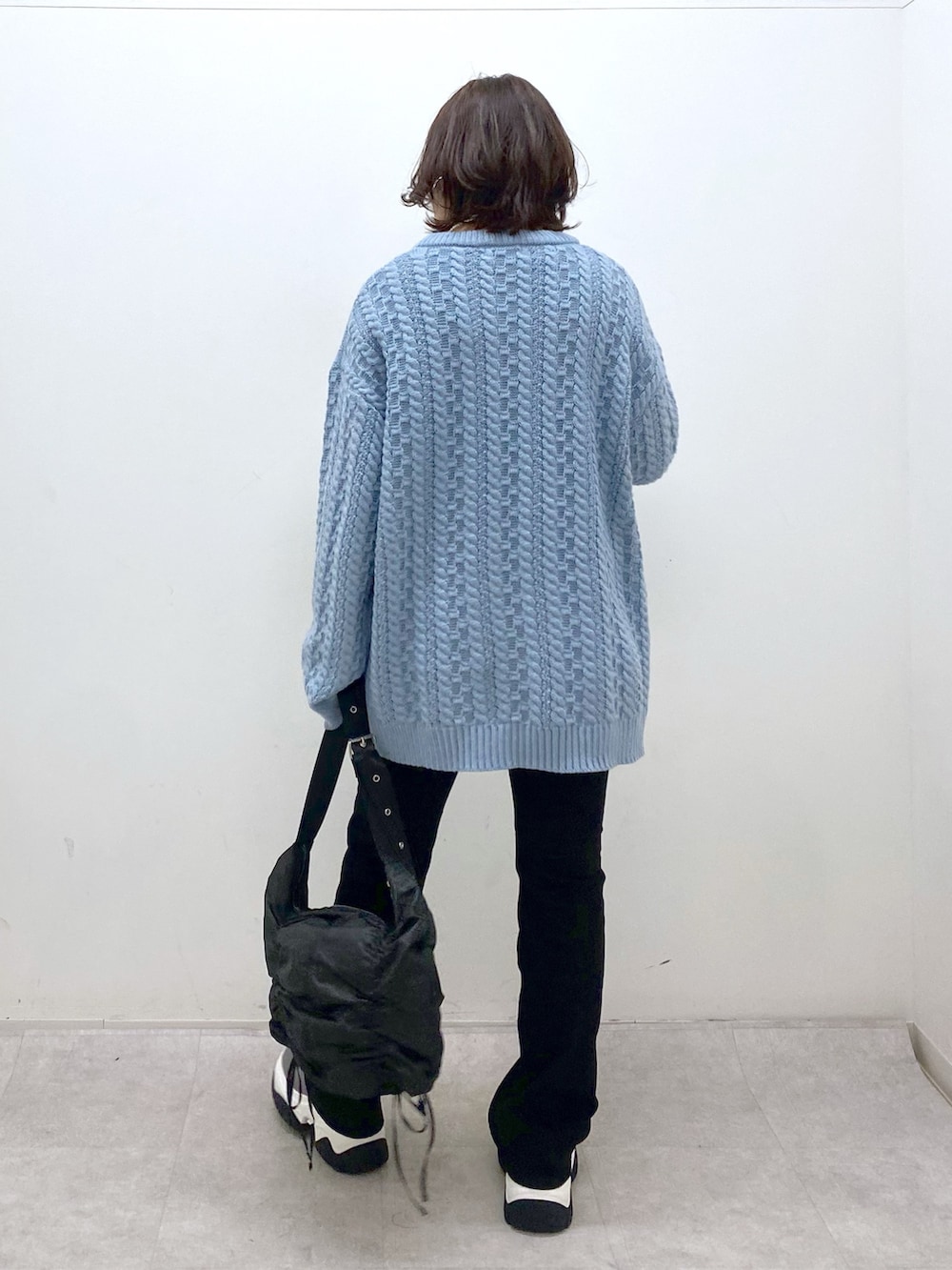 グリーン系のニット/セーター、ブラック系のショルダーバッグ、ブラック系のデニムパンツを着用したレディースの冬コーディネートの5枚目の写真