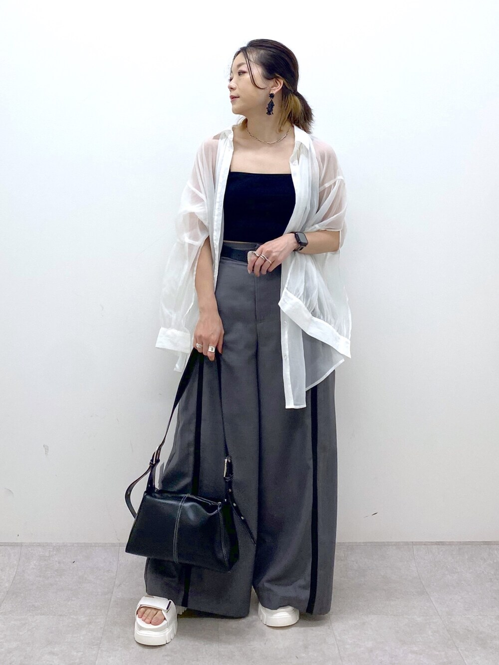 グレー系のスラックス、ブラック系のキャミソール、ブラック系のショルダーバッグを着用したレディースの夏コーディネートの2枚目の写真