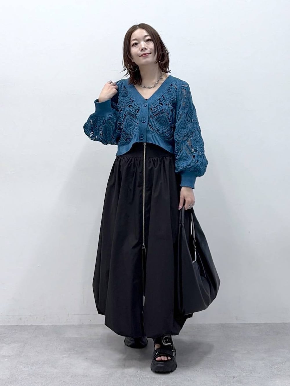 ブルー系のカーディガン/ボレロ、ブラック系のスカートを着用したレディースの春コーディネートの4枚目の写真