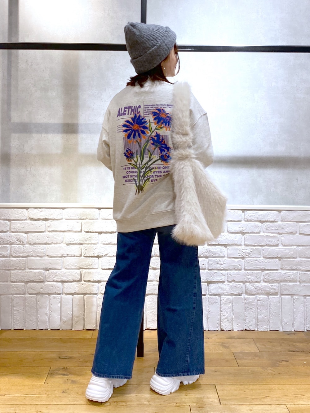 ホワイト系のショルダーバッグ、ブルー系のデニムパンツ、ホワイト系のブーツを着用したレディースの秋コーディネートの6枚目の写真