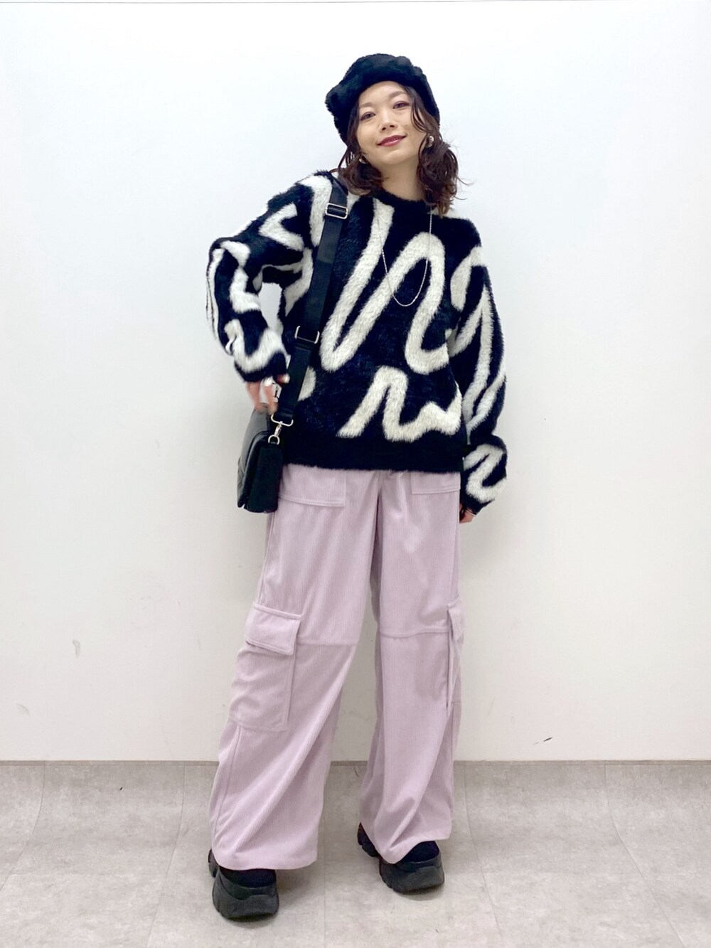 ピンク系のカーゴパンツ、ブラック系のニット/セーター、ブラック系のショルダーバッグを着用したレディースの冬コーディネートの2枚目の写真