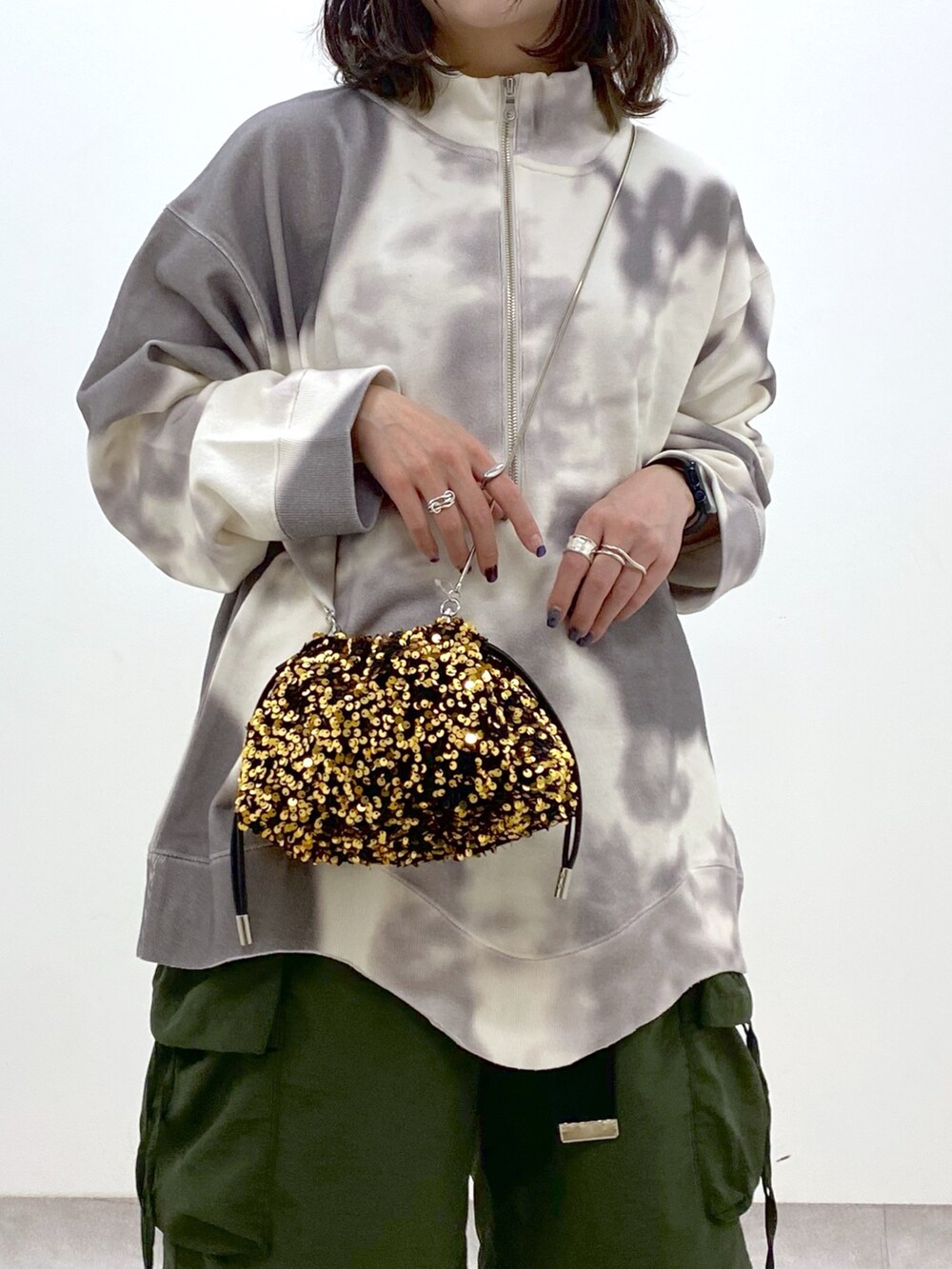 グリーン系のカーゴパンツ、ホワイト系のブーツ、ゴールド系のショルダーバッグを着用したレディースの冬コーディネートの2枚目の写真