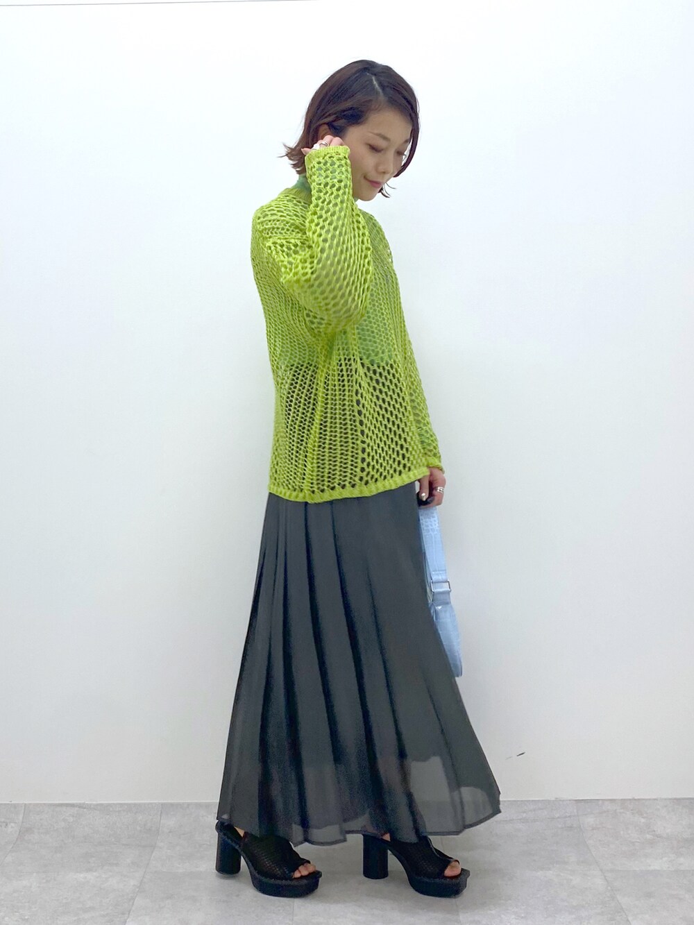 グリーン系のニット/セーター、グリーン系のTシャツ/カットソー、ブラック系のスカートを着用したレディースの春コーディネートの3枚目の写真