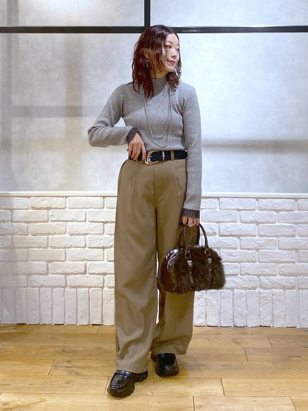 ベージュ系のスラックス、ブラウン系のボストンバッグ、グレー系のニット/セーターを着用したレディースの冬コーディネートの4枚目の写真