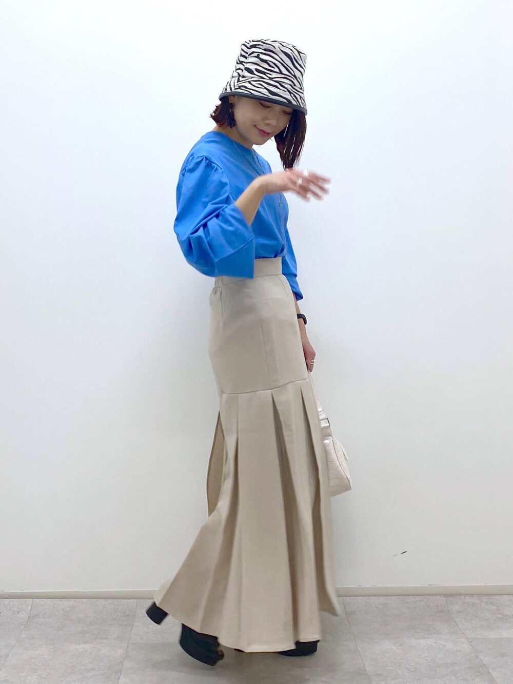 ブルー系のTシャツ/カットソー、ホワイト系のショルダーバッグ、ベージュ系のスカートを着用したレディースの春コーディネートの3枚目の写真