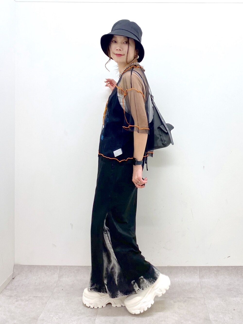 グレー系のショルダーバッグ、ホワイト系のスニーカー、ブラック系のデニムパンツを着用したレディースの春コーディネートの4枚目の写真