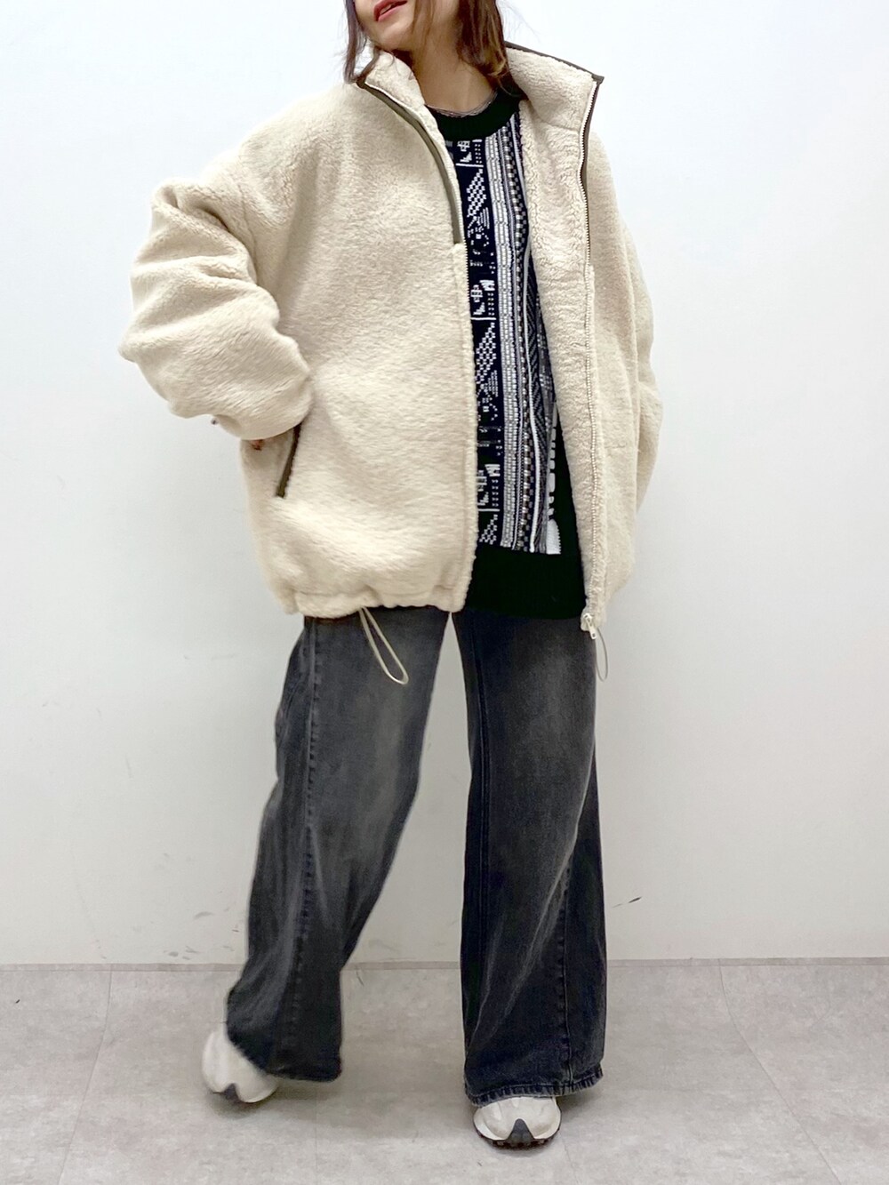 ホワイト系のブルゾン、ブラック系のニット/セーター、ブラック系のデニムパンツを着用したレディースの秋コーディネートの6枚目の写真