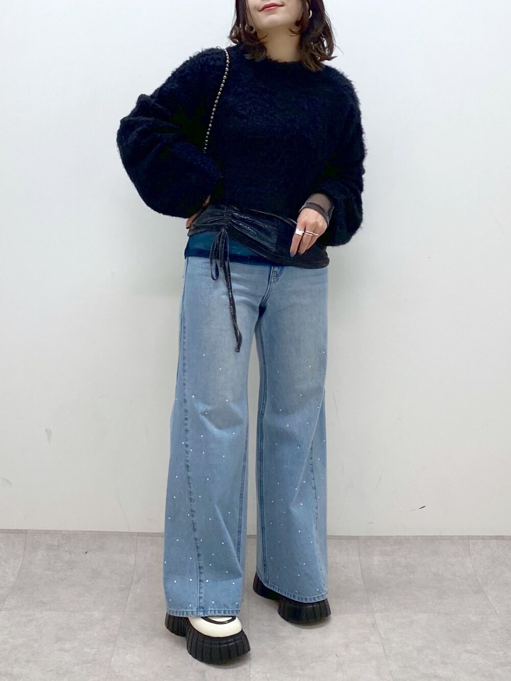 ブラック系のニット/セーター、ブルー系のデニムパンツ、ホワイト系のローファーを着用したレディースの冬コーディネートの8枚目の写真