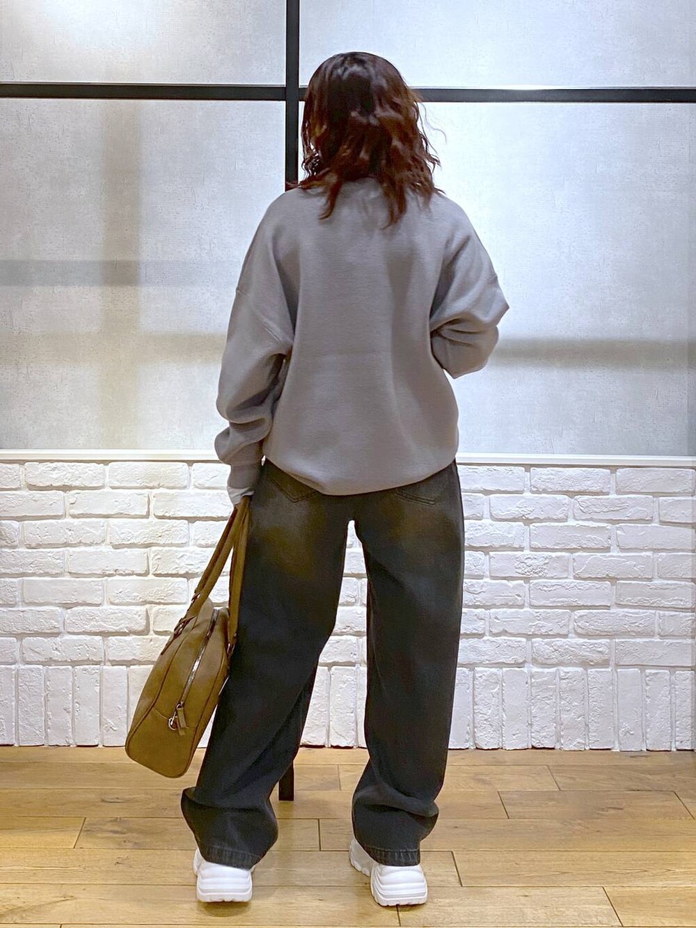 ベージュ系のスニーカー、イエロー系のボストンバッグ、ブラック系のデニムパンツを着用したレディースの秋コーディネートの6枚目の写真