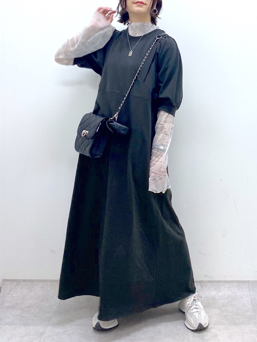 ブラック系のワンピース、ベージュ系のスニーカー、ブラック系のバッグを着用したレディースの春コーディネートの4枚目の写真