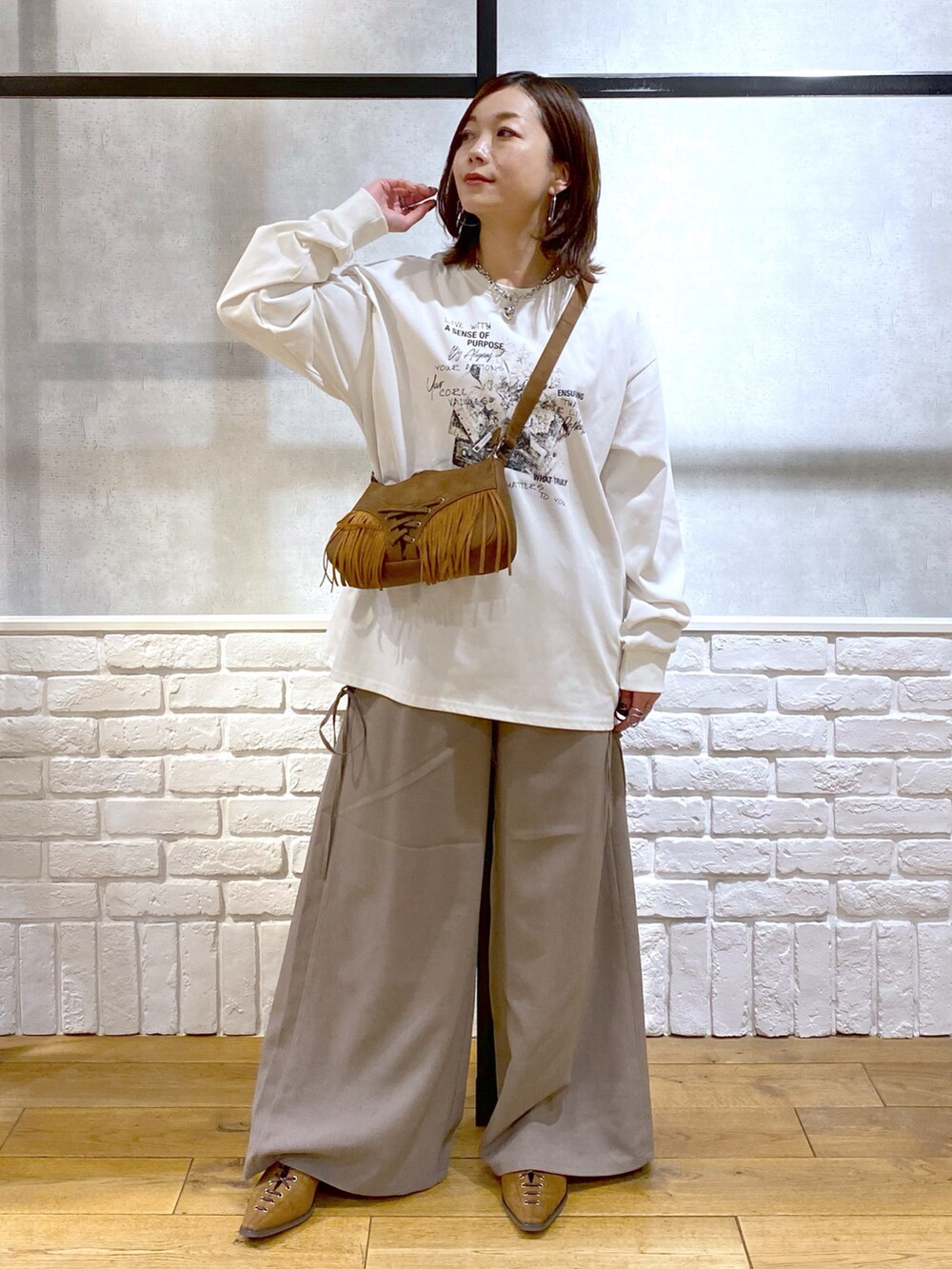 ブラウン系のスラックス、ベージュ系のショルダーバッグ、ブラウン系のパンプスを着用したレディースの春コーディネートの3枚目の写真