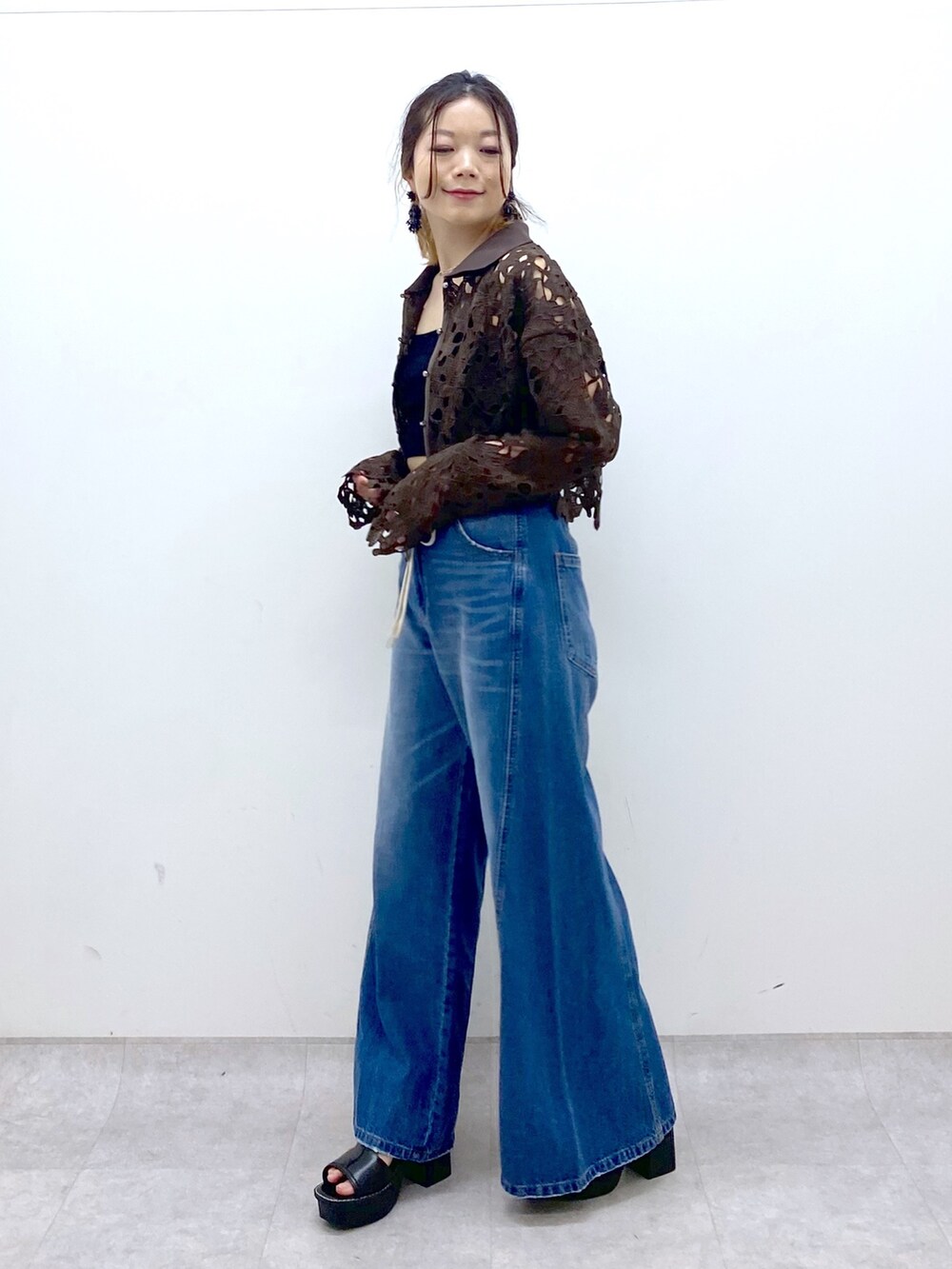 ブルー系のデニムパンツ、ブラウン系のカーディガン/ボレロ、ブラック系のキャミソールを着用したレディースの夏コーディネートの3枚目の写真