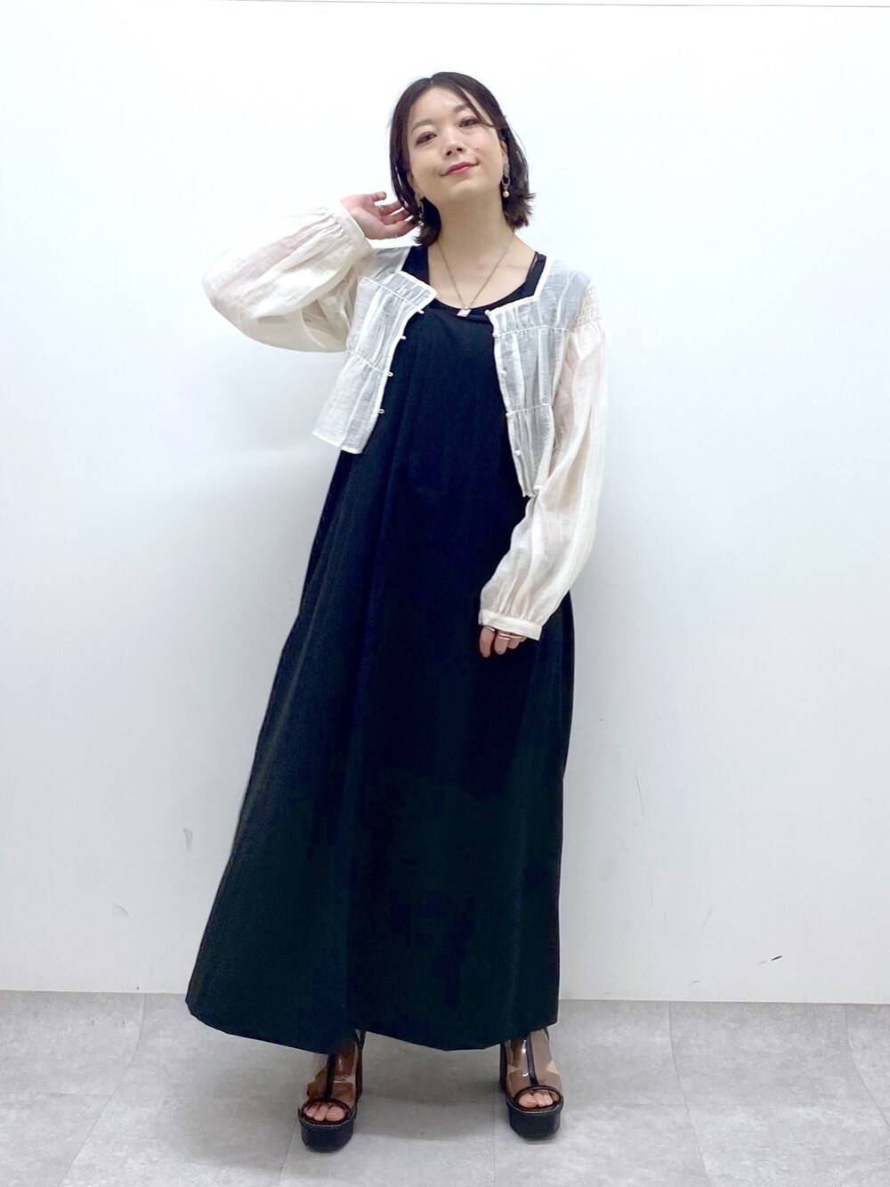 ブラック系のジャンパースカート、ホワイト系のシャツ/ブラウス、その他のサンダルを着用したレディースの夏コーディネートの7枚目の写真