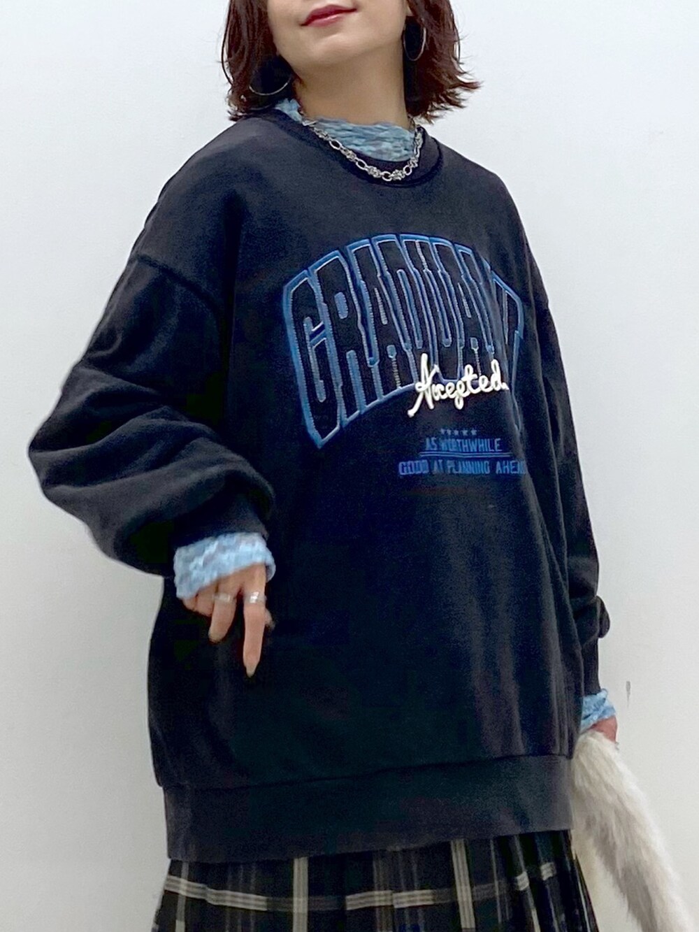 グレー系のスウェット、ブルー系のスカート、ホワイト系のショルダーバッグを着用したレディースの秋コーディネートの2枚目の写真