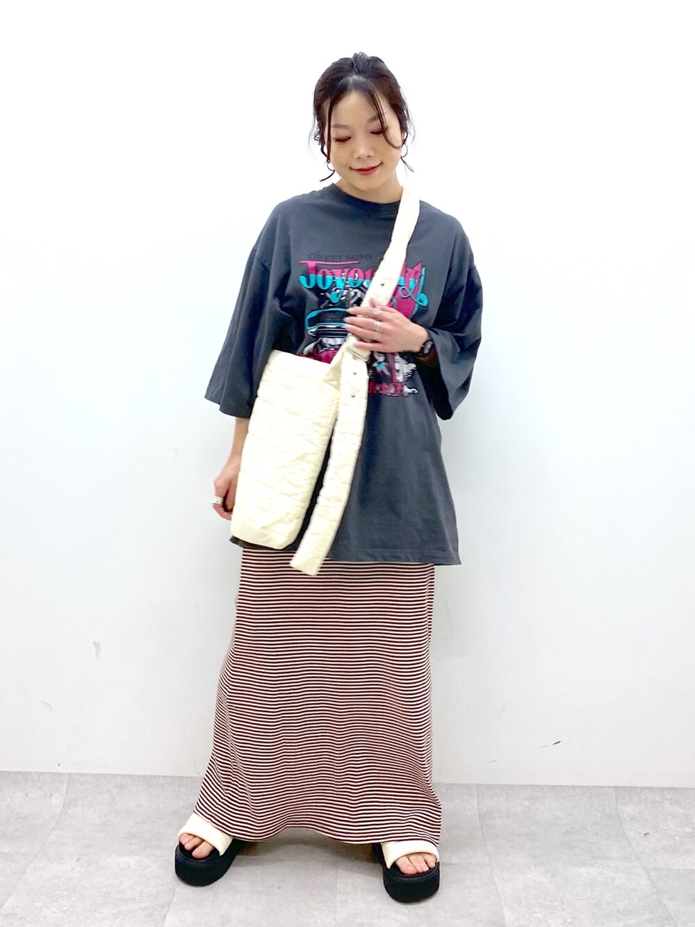 ブラウン系のワンピース、グレー系のTシャツ/カットソー、ホワイト系のショルダーバッグを着用したレディースの春コーディネートの2枚目の写真