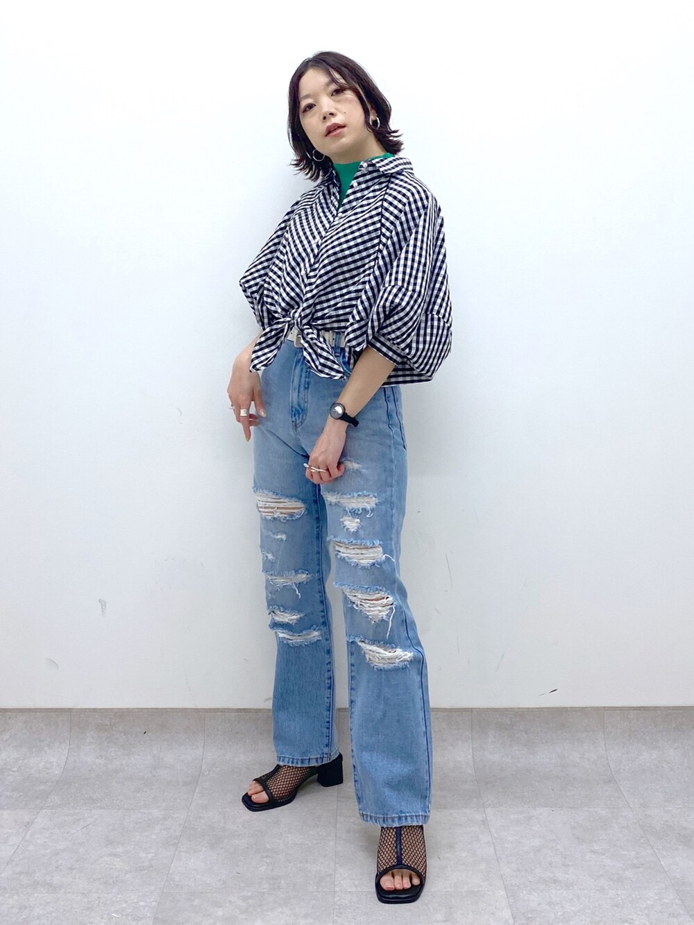 ブルー系のパンツ、ブラック系のシューズ、グリーン系のトップスを着用したレディースの春コーディネートの2枚目の写真