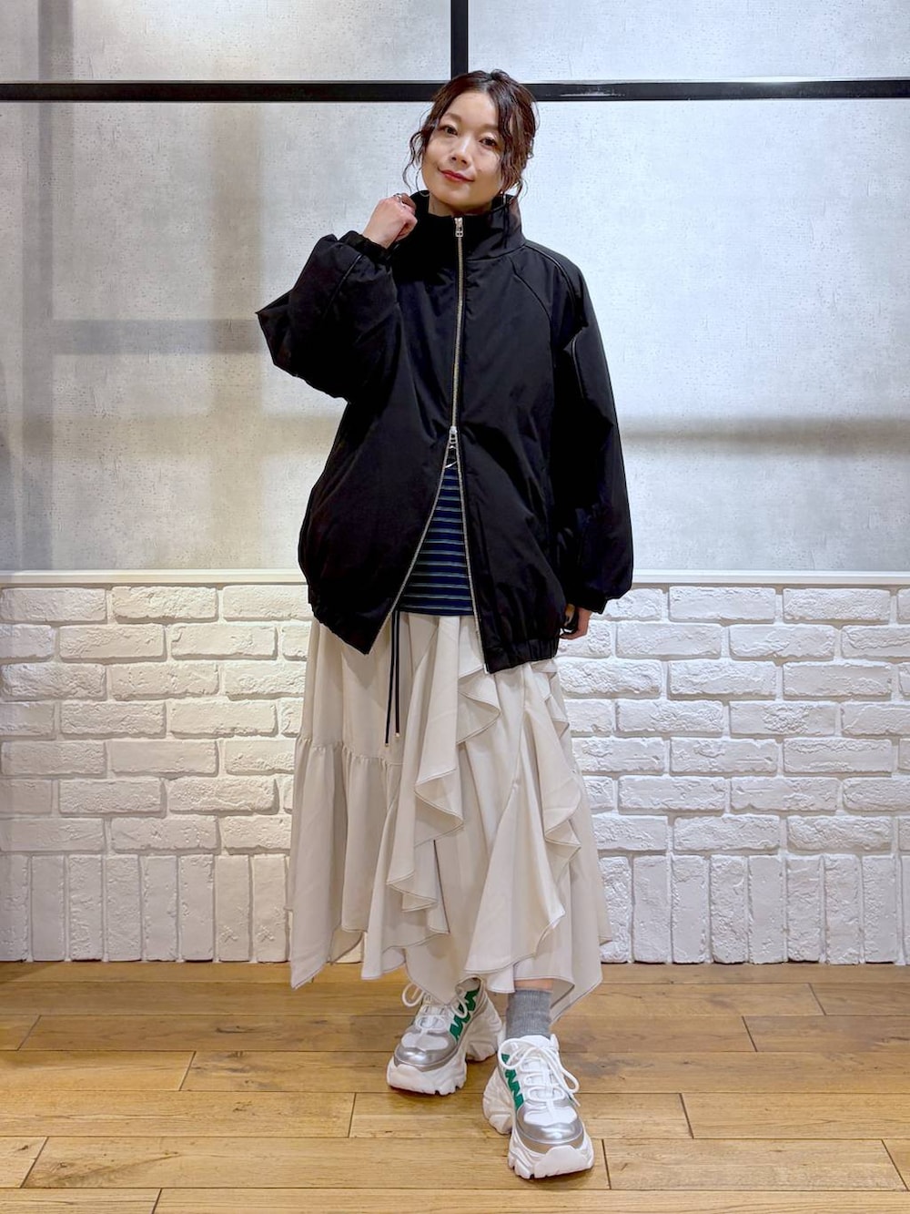 ホワイト系のスニーカー、ベージュ系のスカート、ブラック系のナイロンジャケットを着用したレディースの冬コーディネートの8枚目の写真