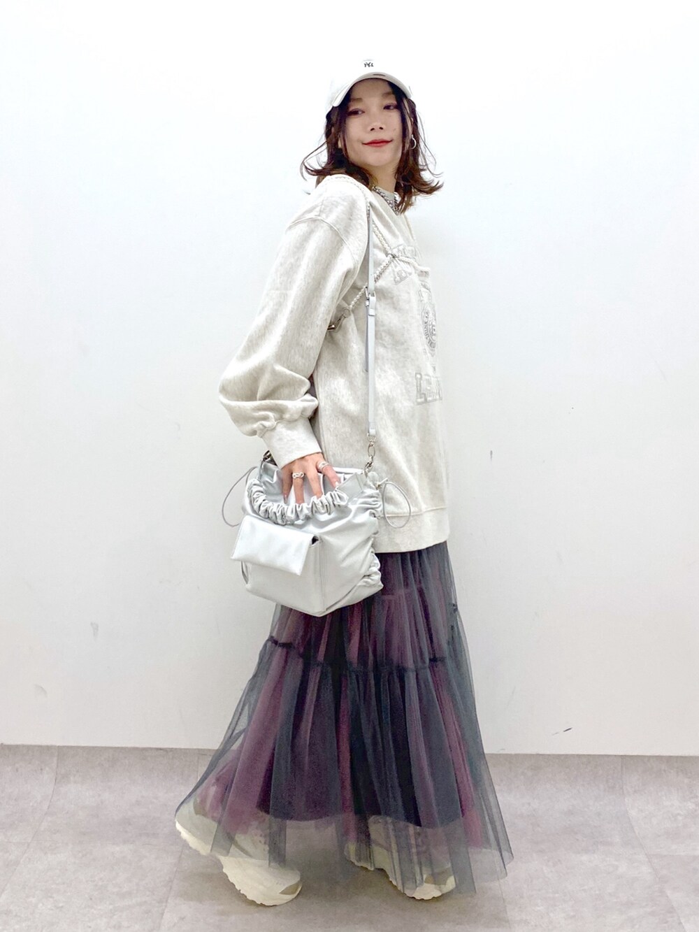 ベージュ系のスウェット、シルバー系のショルダーバッグ、グレー系のスカートを着用したレディースの春コーディネートの7枚目の写真