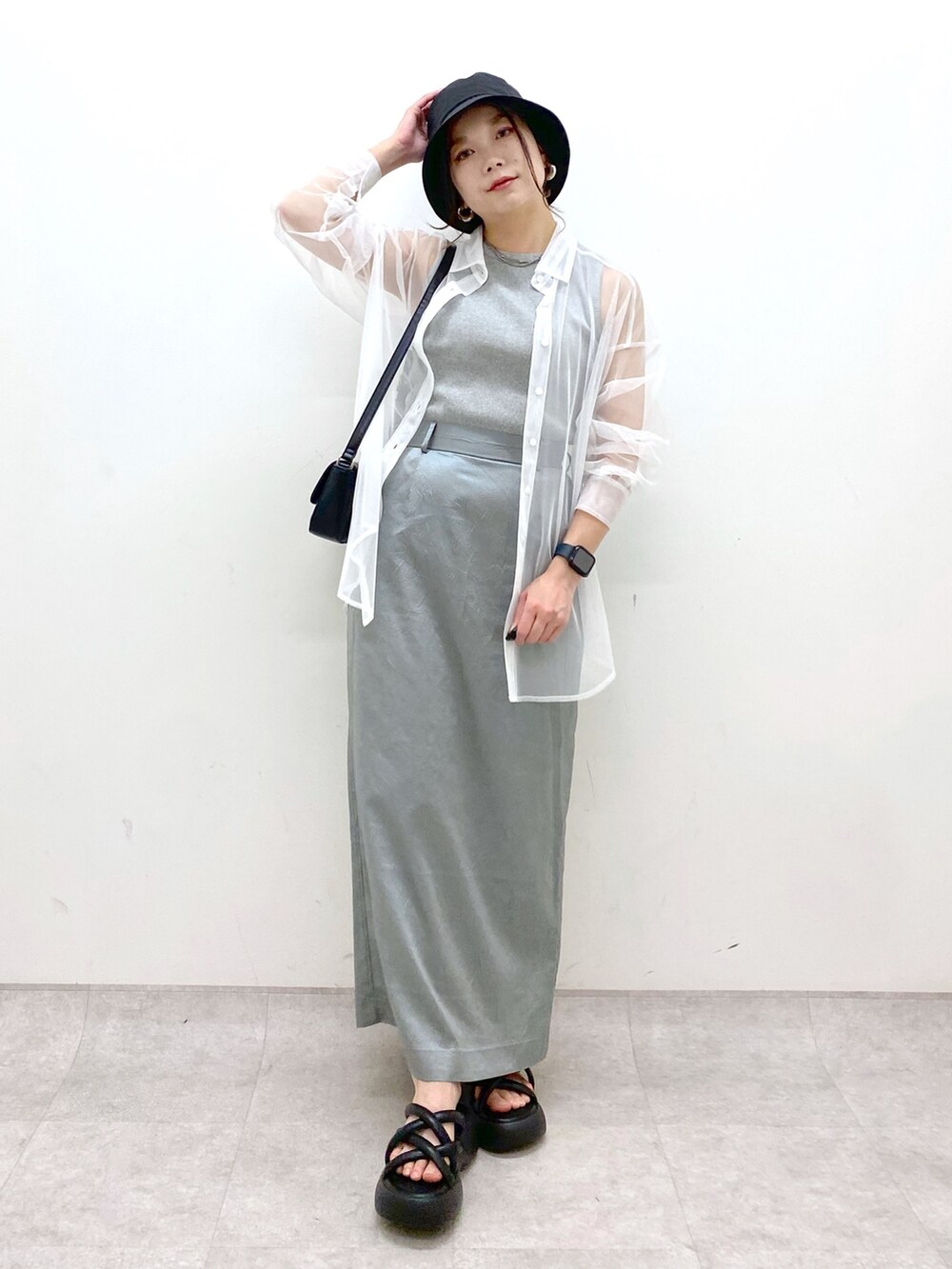 ブルー系のスカート、ブラック系のハンドバッグ、ブラック系のサンダルを着用したレディースの春コーディネートの4枚目の写真