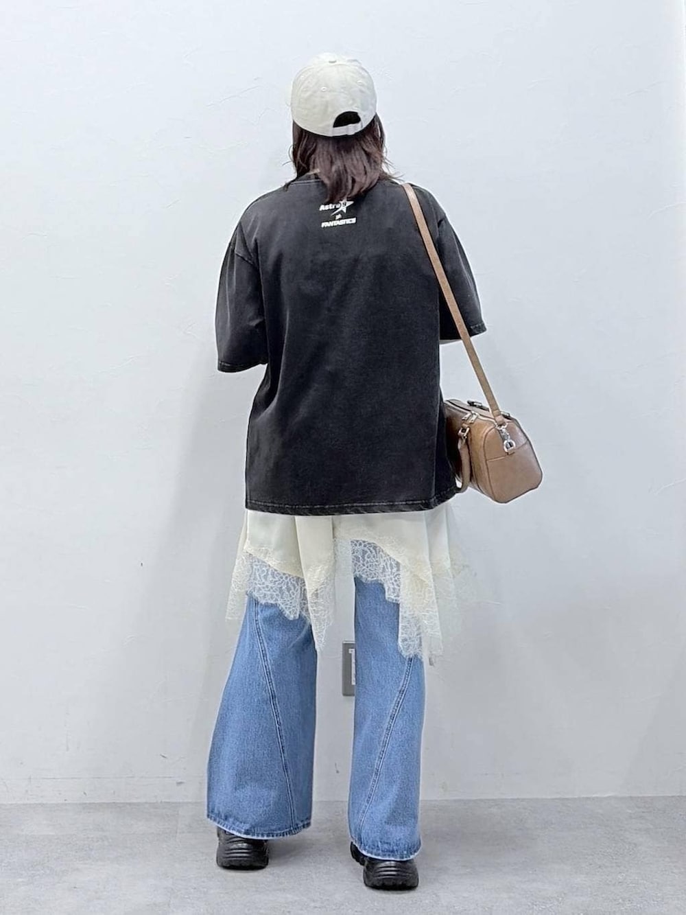 ブルー系のデニムパンツ、ブラウン系のボストンバッグ、ホワイト系のチュニックを着用したレディースの春コーディネートの6枚目の写真