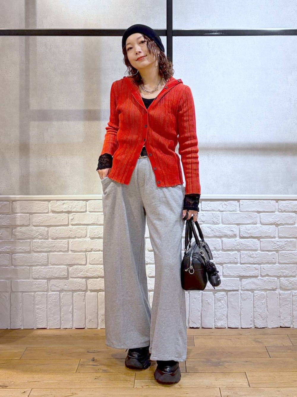 ブラック系のスニーカー、ブラック系のボストンバッグ、レッド系のカーディガン/ボレロを着用したレディースの春コーディネートの4枚目の写真