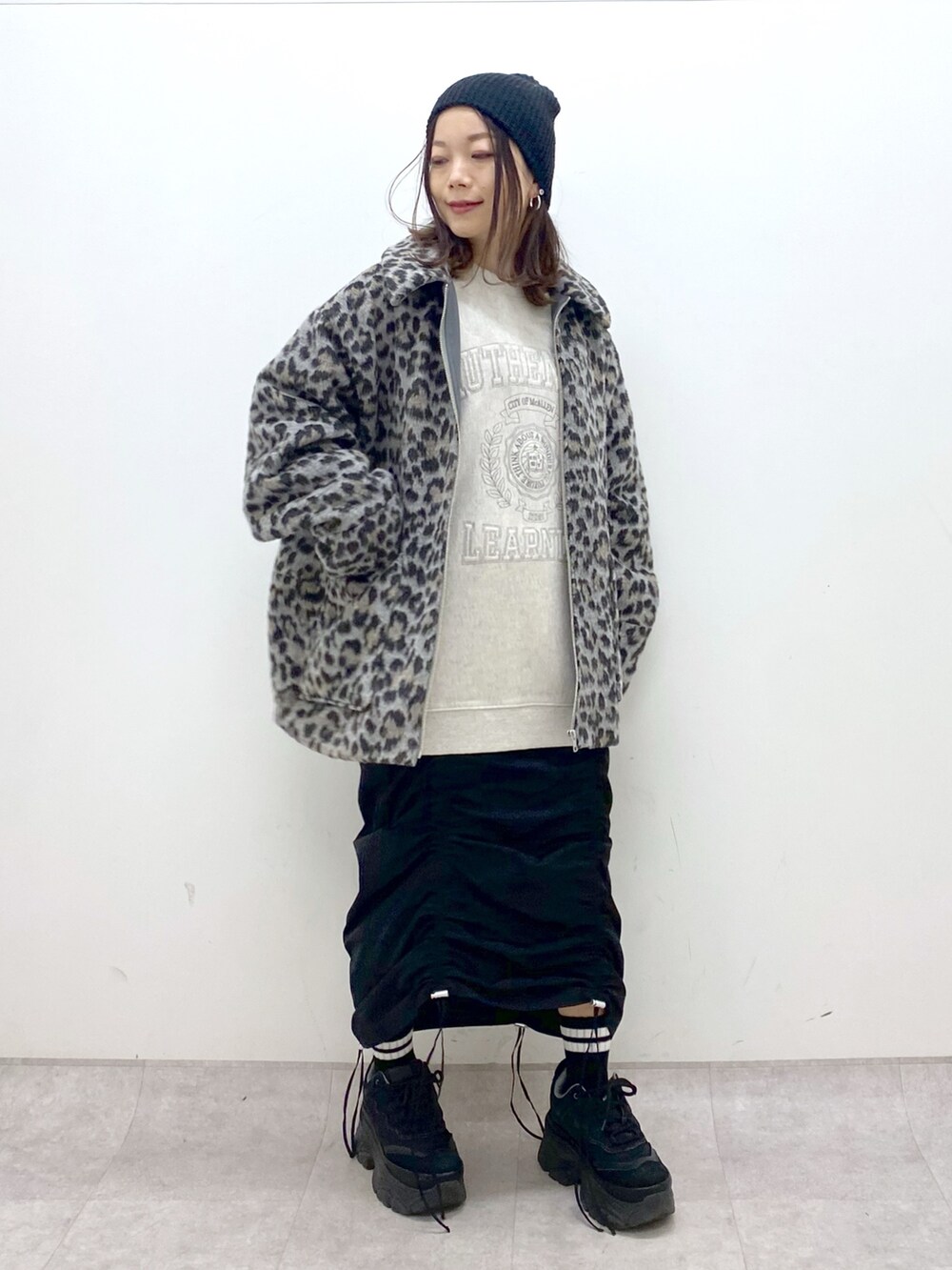 ベージュ系のスウェット、ブラック系のワンピース、ブラック系のスニーカーを着用したレディースの冬コーディネートの2枚目の写真