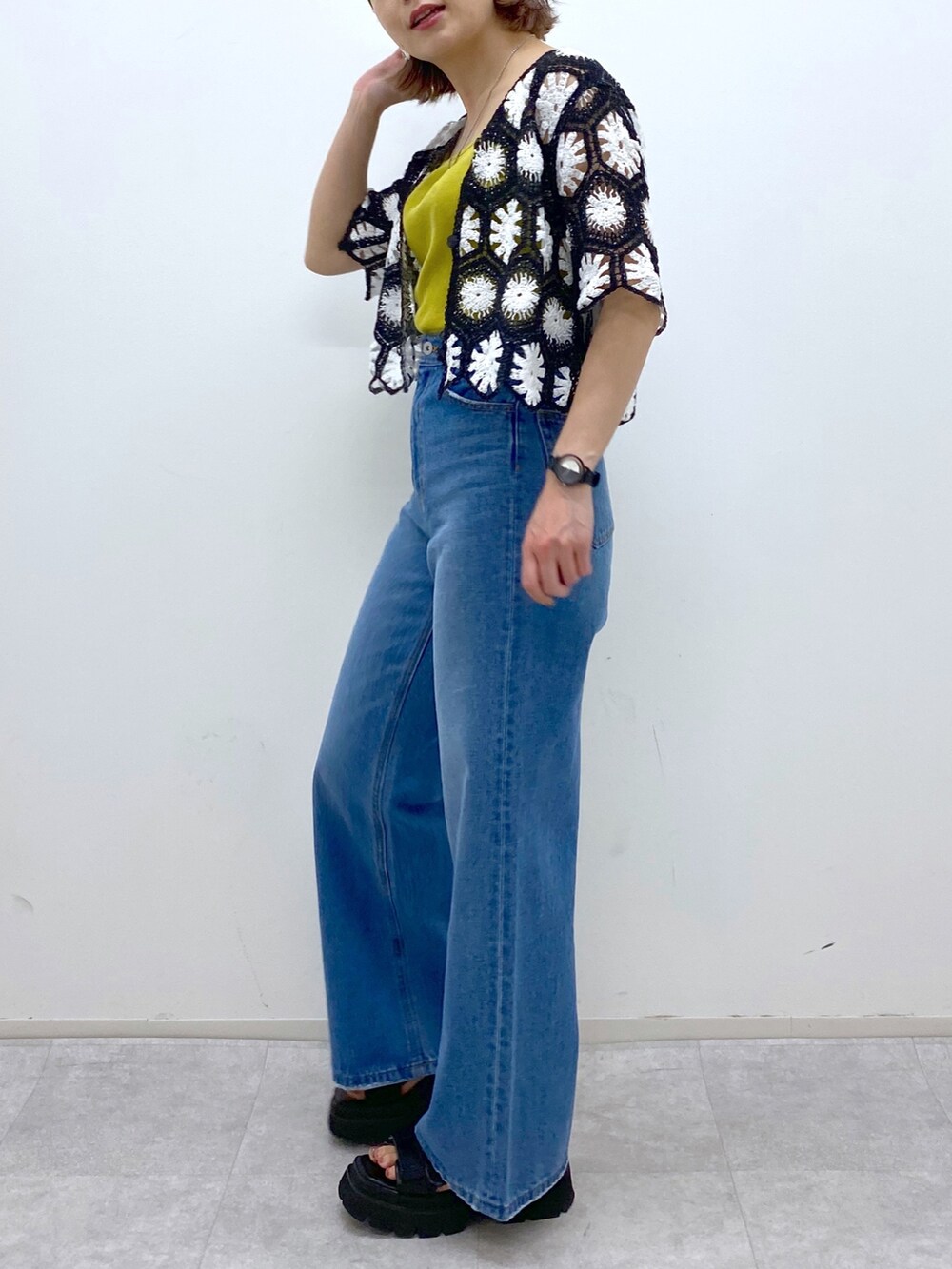 ブラック系のサンダル、イエロー系のタンクトップ、ブルー系のパンツを着用したレディースの夏コーディネートの4枚目の写真