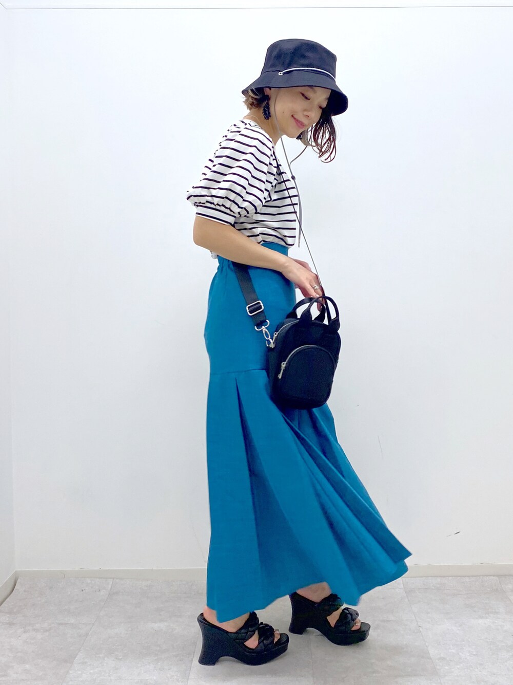 ブルー系のスカート、ブラック系のサンダル、ブラック系のショルダーバッグを着用したレディースの夏コーディネートの2枚目の写真