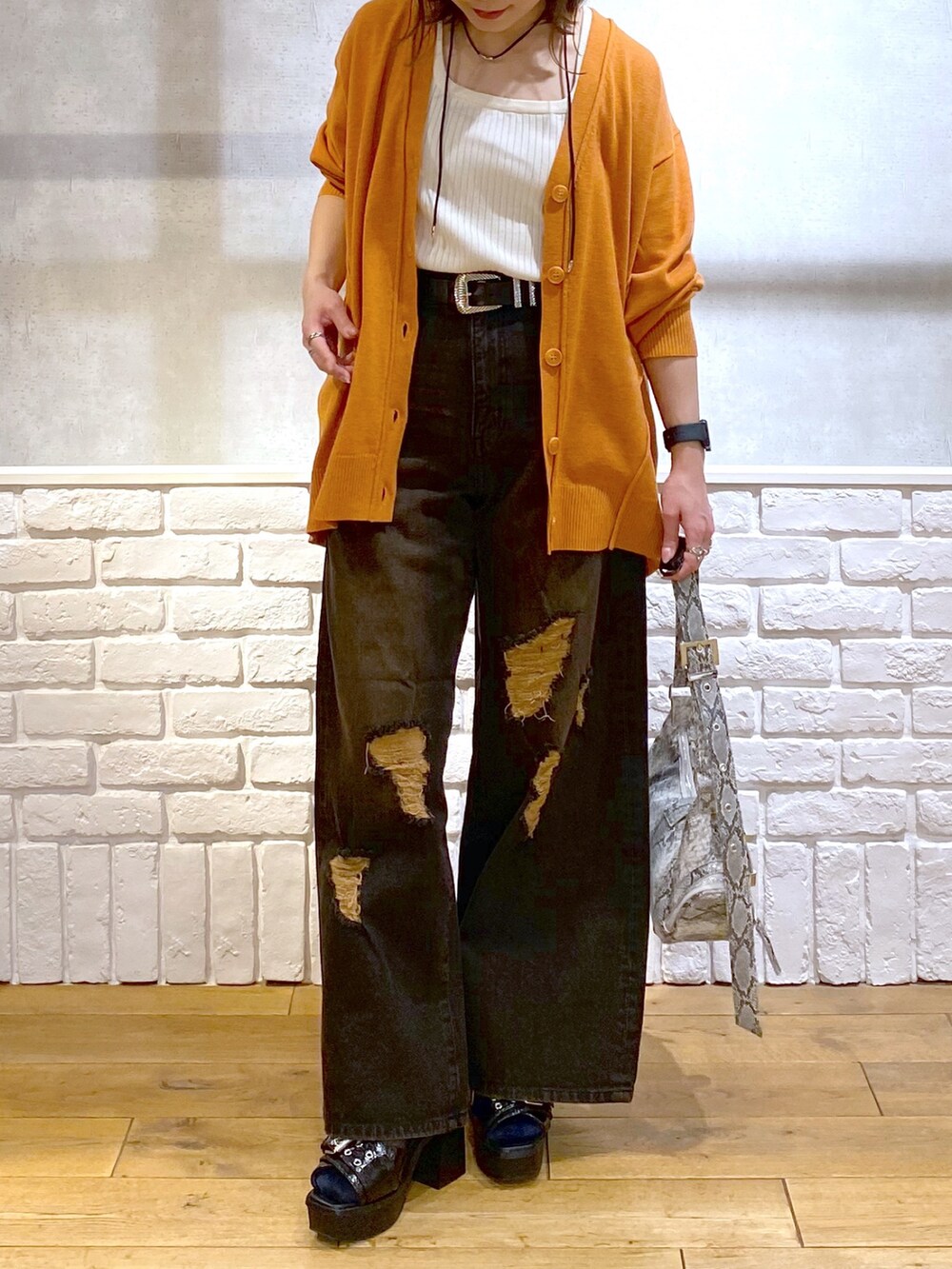 ホワイト系のタンクトップ、オレンジ系のカーディガン/ボレロ、ブラック系のデニムパンツを着用したレディースの春コーディネートの3枚目の写真