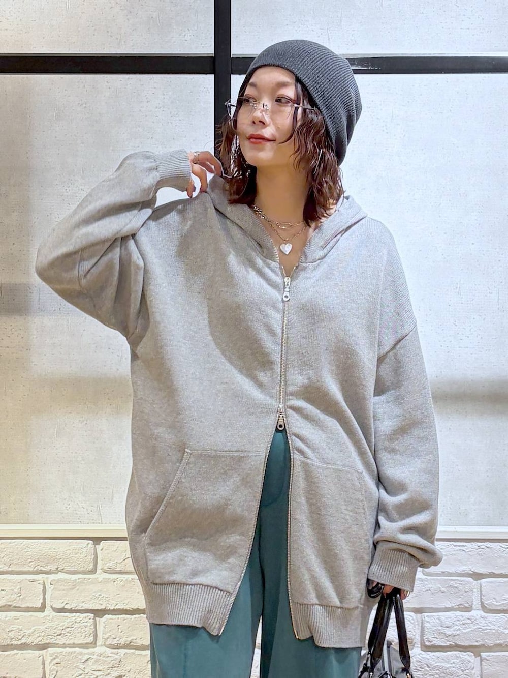 グレー系のスニーカー、グレー系のパーカー、ブラック系のショルダーバッグを着用したレディースの春コーディネートの2枚目の写真