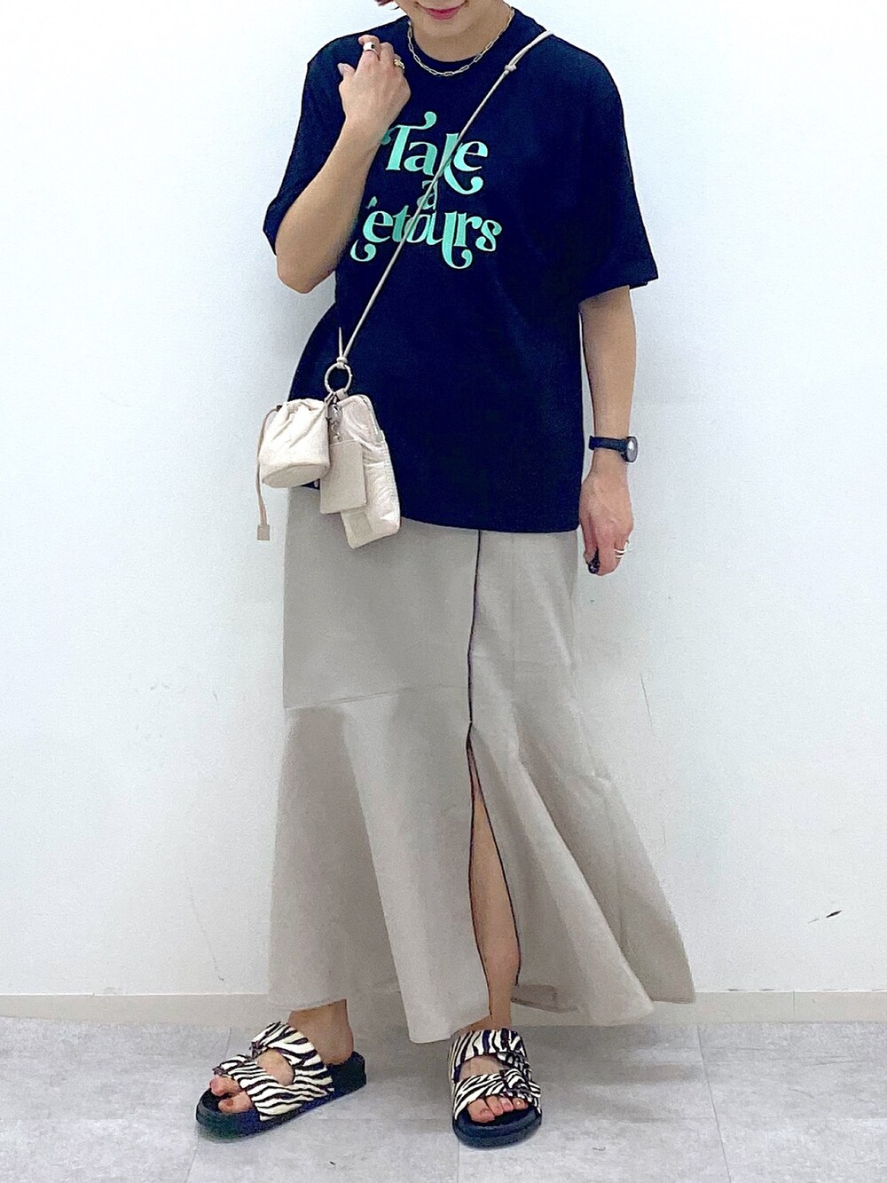 ベージュ系のショルダーバッグ、ベージュ系のスカート、ブラック系のTシャツ/カットソーを着用したレディースの夏コーディネートの5枚目の写真