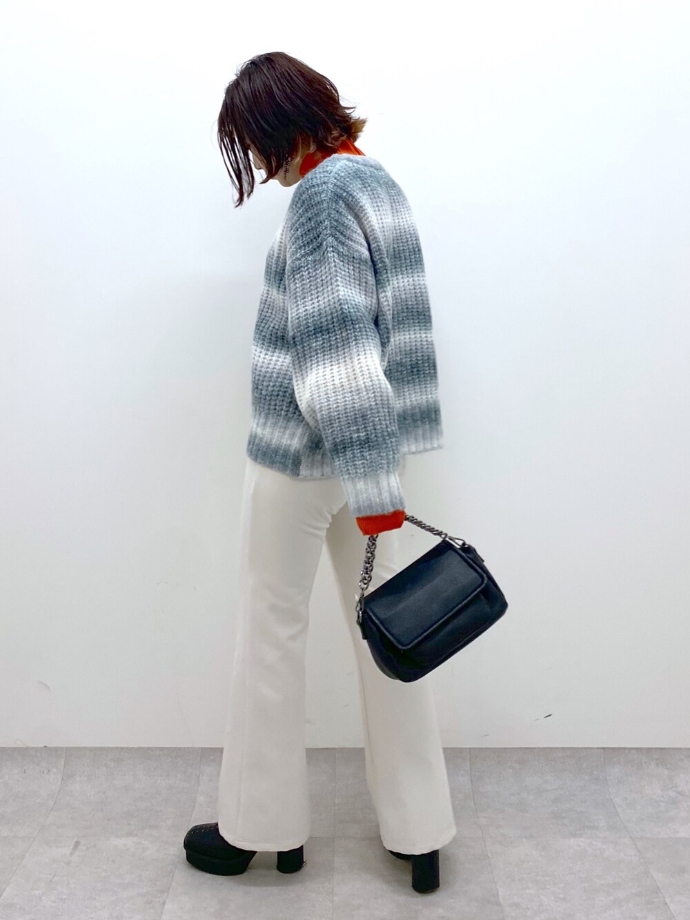 ブラック系のトップス、オレンジ系のトップス、ブラック系のバッグを着用したレディースの秋コーディネートの3枚目の写真