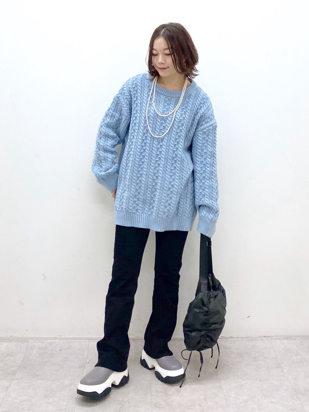 グリーン系のニット/セーター、ブラック系のショルダーバッグ、ブラック系のデニムパンツを着用したレディースの冬コーディネートの8枚目の写真