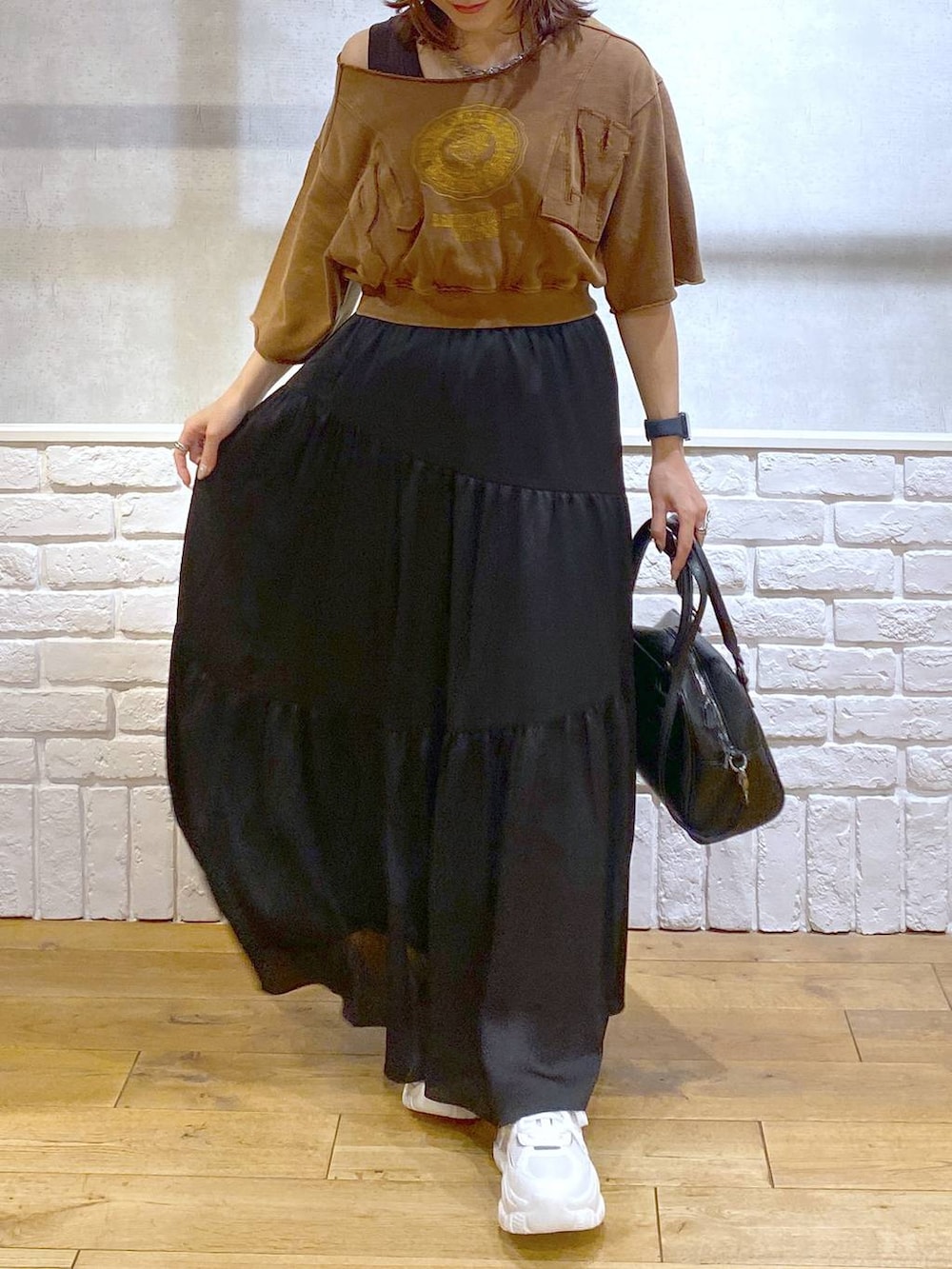 ブラウン系のタンクトップ、ブラック系のショルダーバッグ、ホワイト系のスニーカーを着用したレディースの夏コーディネートの3枚目の写真