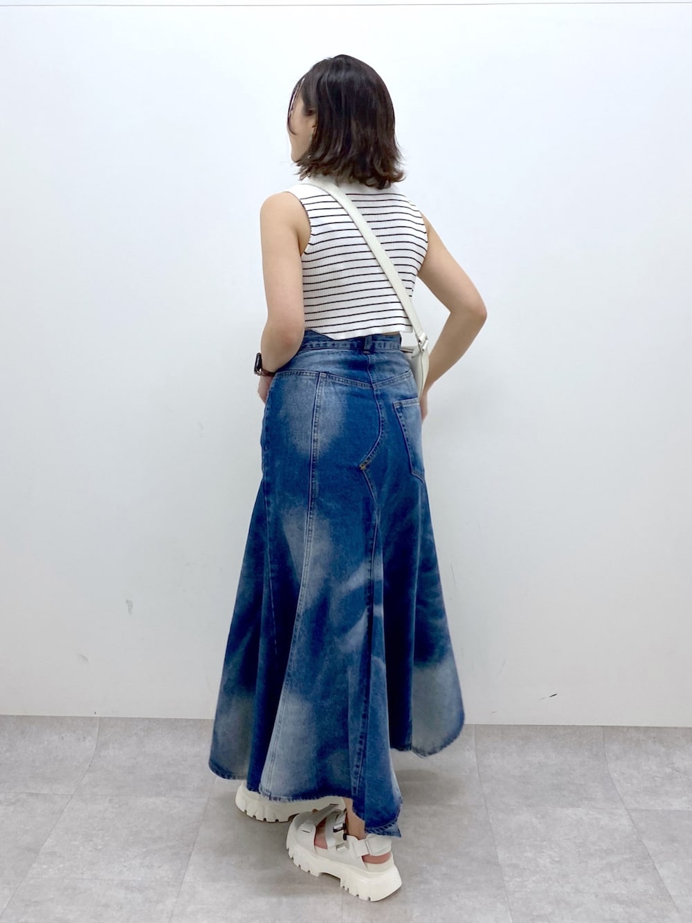 ホワイト系のショルダーバッグ、ブルー系のスカート、ホワイト系のTシャツ/カットソーを着用したレディースの夏コーディネートの4枚目の写真