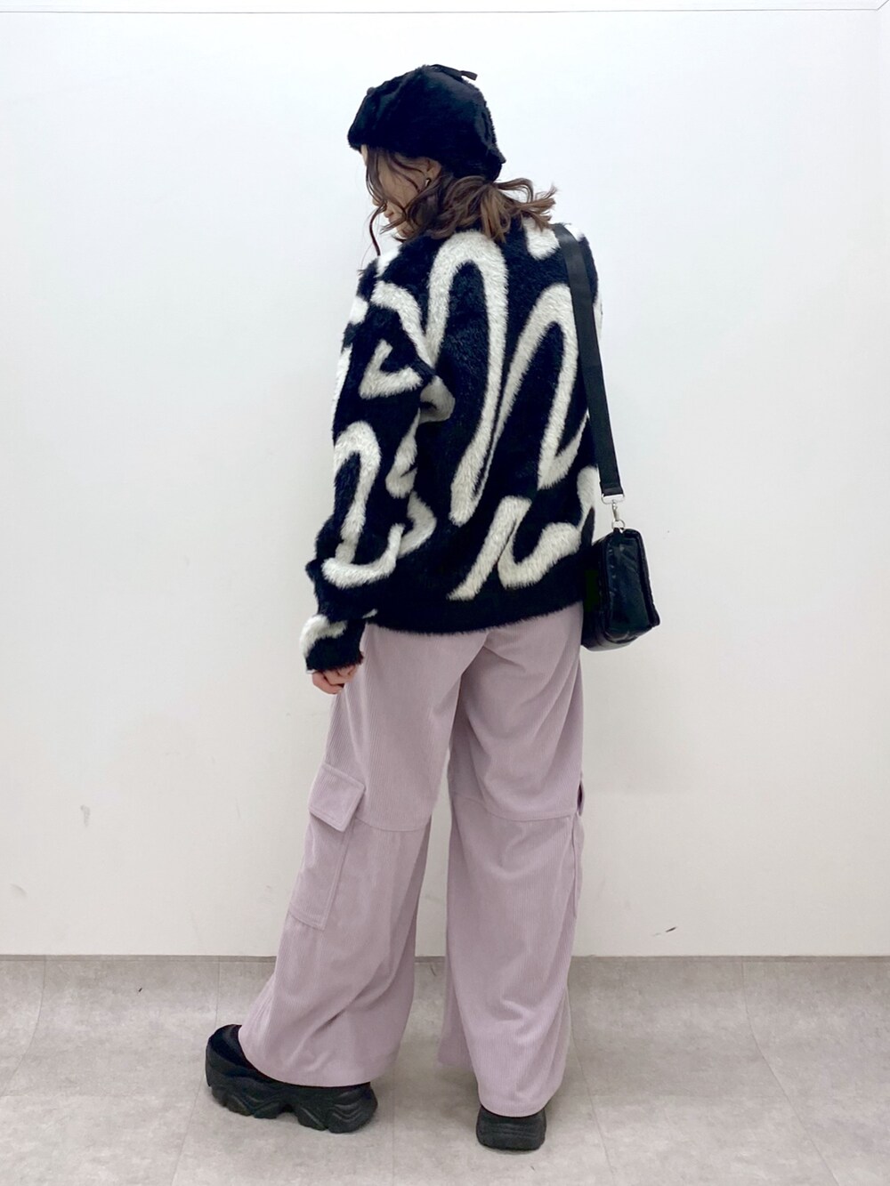 ピンク系のカーゴパンツ、ブラック系のニット/セーター、ブラック系のショルダーバッグを着用したレディースの冬コーディネートの5枚目の写真