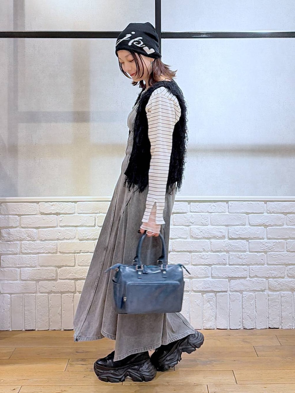 ブラック系のスニーカー、ブラック系のワンピース、ブルー系のショルダーバッグを着用したレディースの冬コーディネートの5枚目の写真