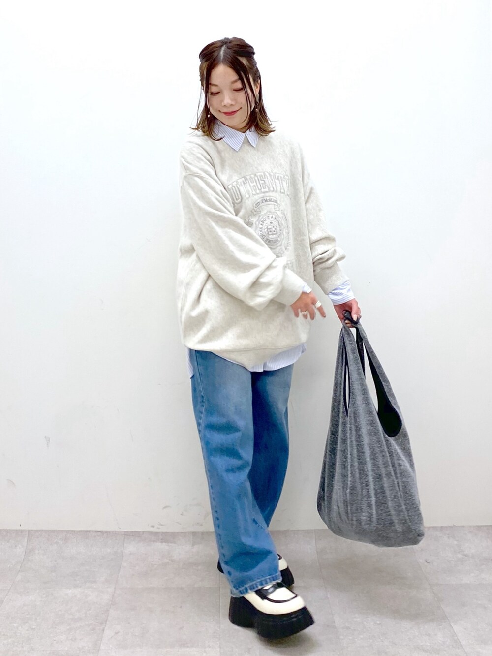 ベージュ系のスウェット、ブルー系のデニムパンツ、ブラック系のトートバッグを着用したレディースの冬コーディネートの4枚目の写真