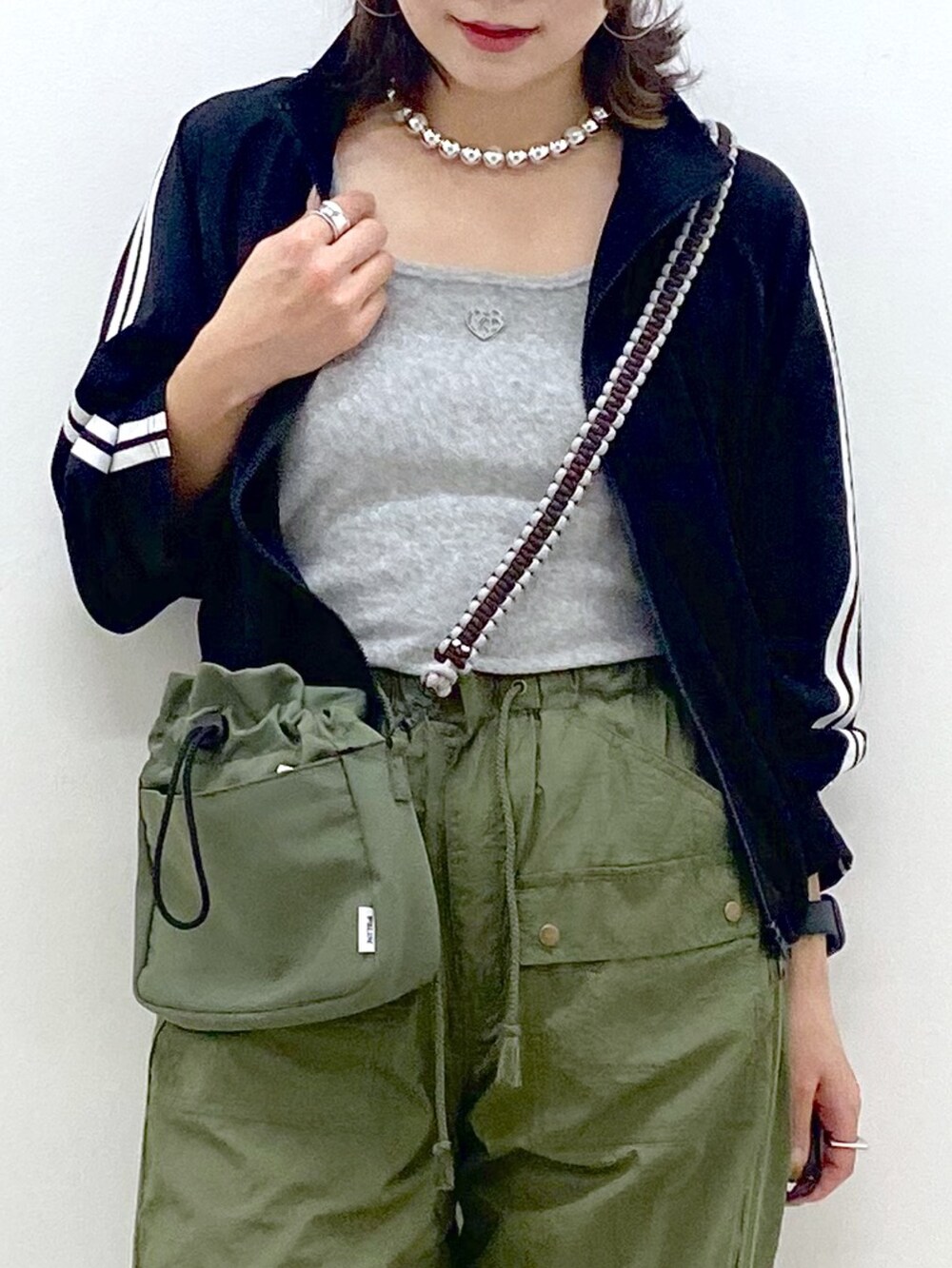 グリーン系のカーゴパンツ、ホワイト系のスニーカー、グリーン系のショルダーバッグを着用したレディースの夏コーディネートの2枚目の写真