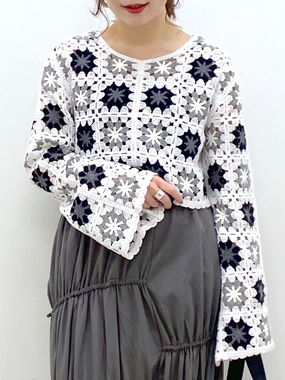 グレー系のスカート、ホワイト系のカーディガン/ボレロ、ブラック系のドラムバッグを着用したレディースの春コーディネートの2枚目の写真