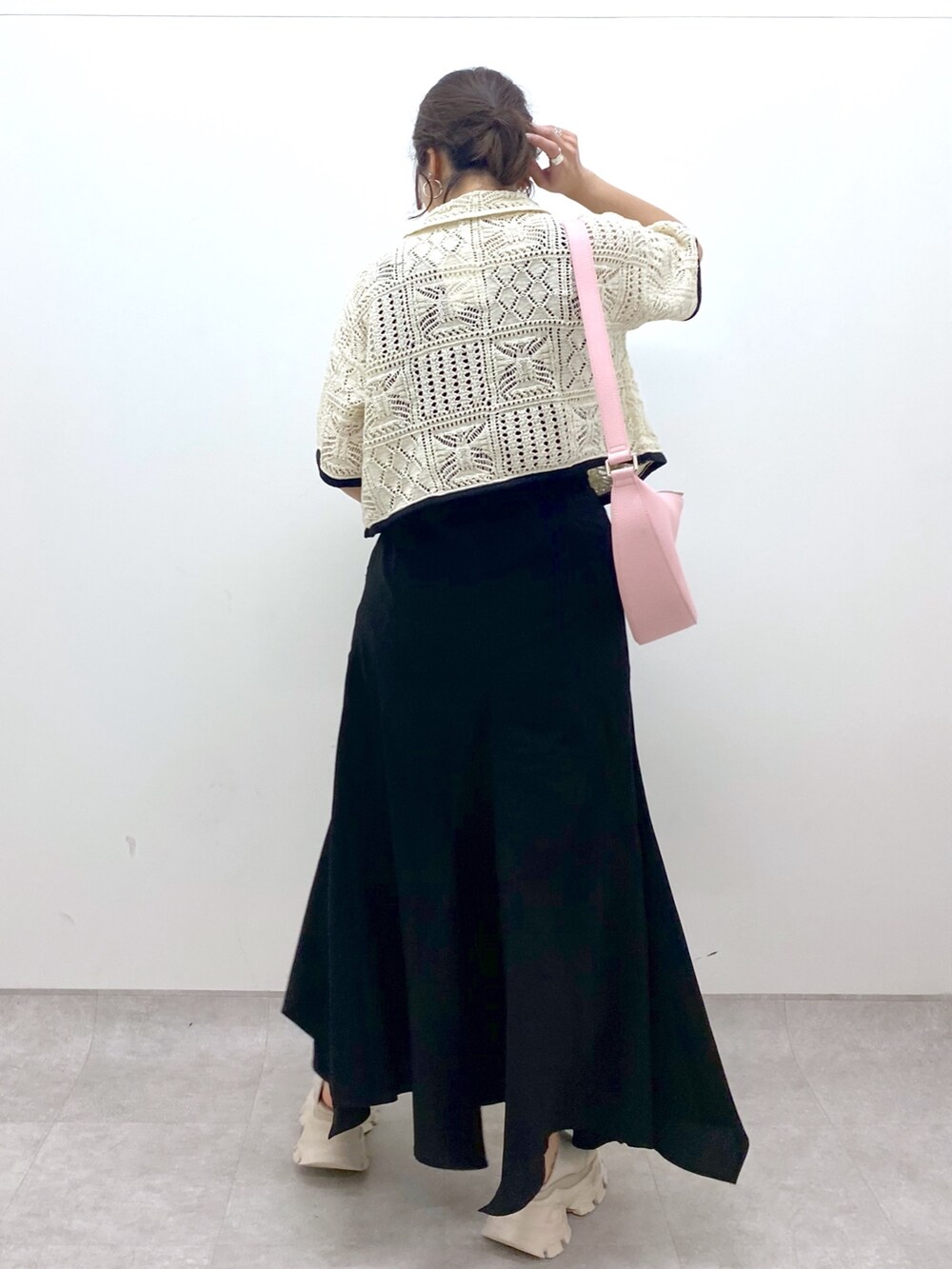 ブラック系のスカート、ホワイト系のカーディガン/ボレロ、ピンク系のショルダーバッグを着用したレディースの夏コーディネートの3枚目の写真