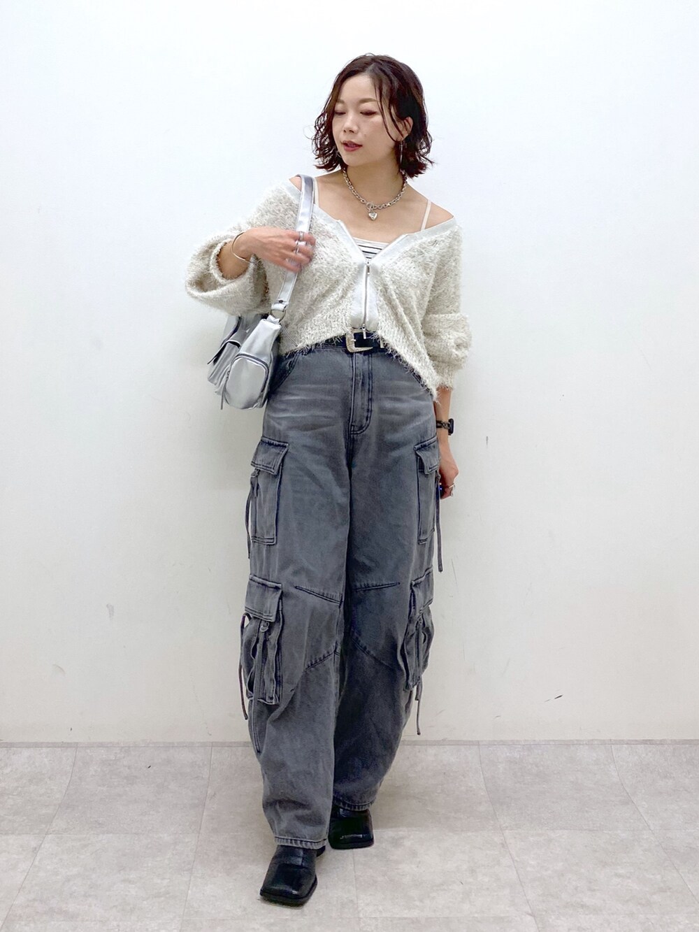 ブラック系のデニムパンツ、ブラック系のブーツ、シルバー系のショルダーバッグを着用したレディースの秋コーディネートの8枚目の写真