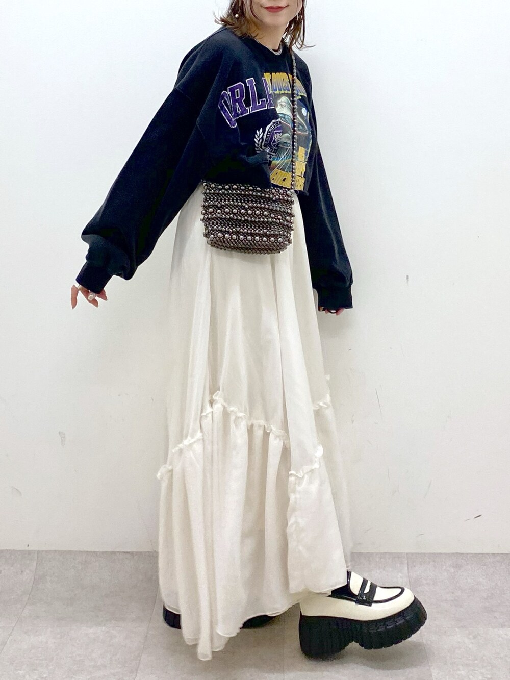 ブラック系のスウェット、ブラック系のショルダーバッグ、ホワイト系のスカートを着用したレディースの冬コーディネートの3枚目の写真