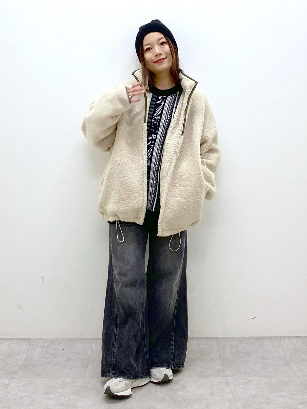 ホワイト系のブルゾン、ブラック系のニット/セーター、ブラック系のデニムパンツを着用したレディースの秋コーディネートの2枚目の写真