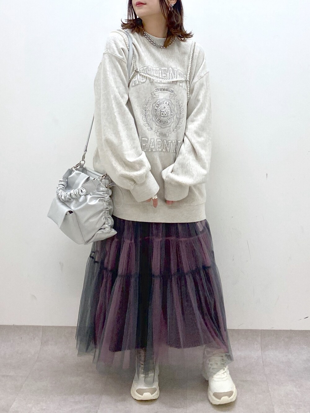 ベージュ系のスウェット、シルバー系のショルダーバッグ、グレー系のスカートを着用したレディースの春コーディネートの3枚目の写真