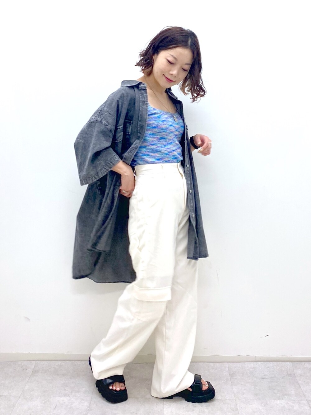 ホワイト系のカーゴパンツ、ブルー系のタンクトップ、ブラック系のサンダルを着用したレディースの夏コーディネートの4枚目の写真