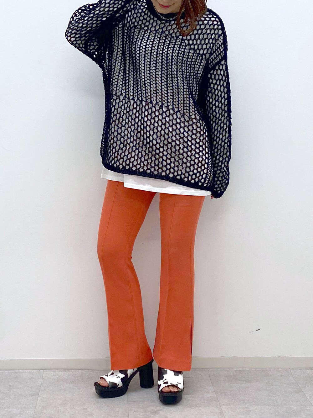 オレンジ系のその他パンツ、ホワイト系のサンダル、ブラック系のニット/セーターを着用したレディースの春コーディネートの5枚目の写真