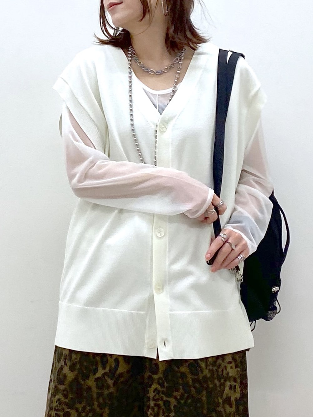 ホワイト系のカーディガン/ボレロ、ホワイト系のTシャツ/カットソー、ブラック系のバックパック/リュックを着用したレディースの春コーディネートの2枚目の写真