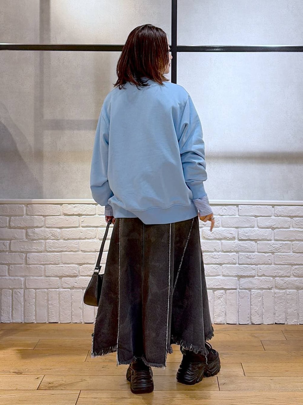 ブラック系のスニーカー、ブラック系のハンドバッグ、ブラック系のデニムスカートを着用したレディースの春コーディネートの6枚目の写真