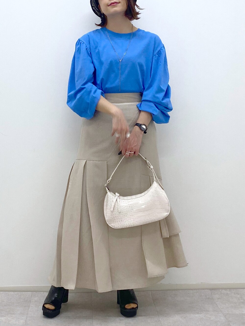 ブルー系のTシャツ/カットソー、ホワイト系のショルダーバッグ、ベージュ系のスカートを着用したレディースの春コーディネートの5枚目の写真